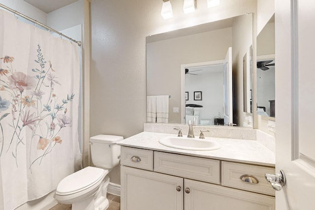 bathroom with vanity, toilet, ceiling fan, and curtained shower