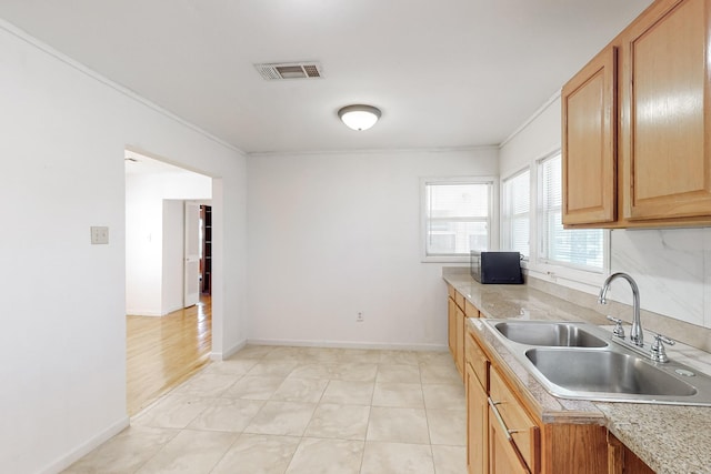 kitchen featuring crown molding, sink, and light tile patterned flooring