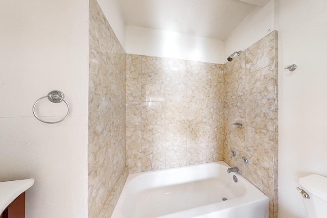 bathroom with toilet and tiled shower / bath