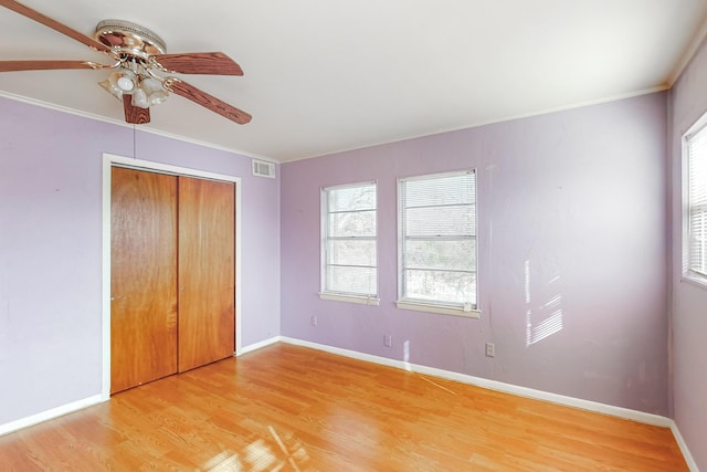 unfurnished bedroom with ceiling fan, light wood-type flooring, multiple windows, and a closet