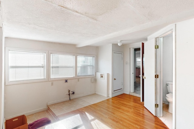 unfurnished bedroom featuring ensuite bath, hardwood / wood-style floors, and a textured ceiling