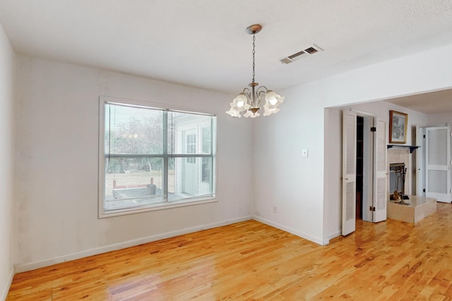 spare room with wood-type flooring and a notable chandelier