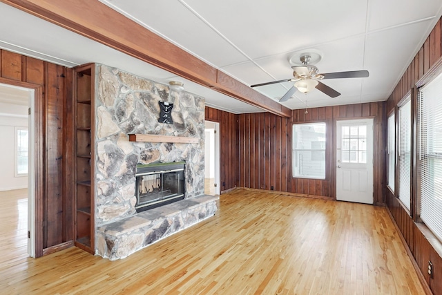 unfurnished living room featuring light hardwood / wood-style flooring, a stone fireplace, and ceiling fan