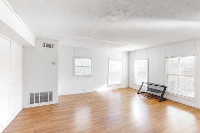 unfurnished living room featuring light hardwood / wood-style floors and a textured ceiling