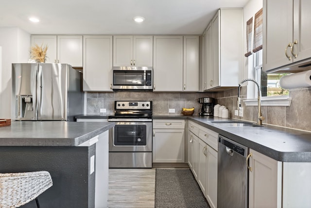 1813 Aslynn Cir, Aubrey, TX 76227 - kitchen with appliances with stainless steel finishes, a sink, dark countertops, light wood-style floors, and backsplash