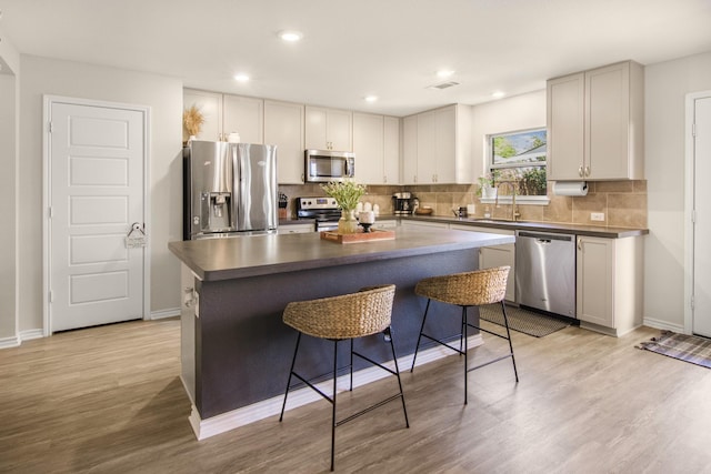 kitchen featuring sink, a center island, stainless steel appliances, light hardwood / wood-style flooring, and a breakfast bar area