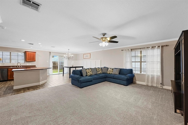 living room featuring ceiling fan with notable chandelier, sink, ornamental molding, and carpet floors