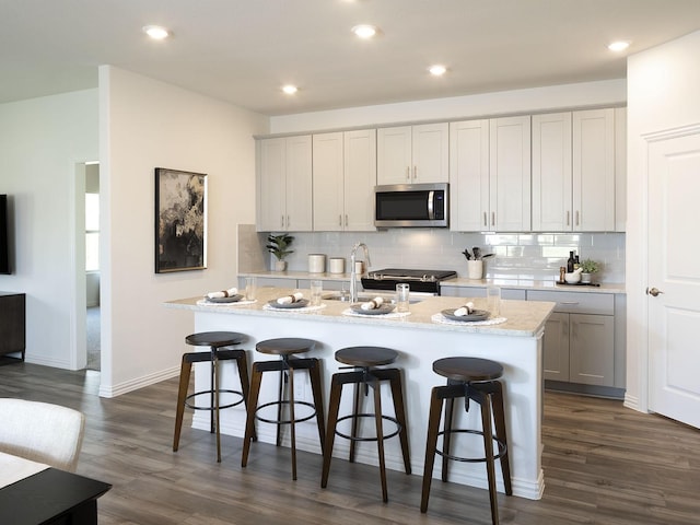 kitchen with a breakfast bar area, dark hardwood / wood-style flooring, and a center island with sink