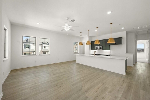 kitchen featuring a sink, visible vents, open floor plan, light countertops, and light wood-type flooring