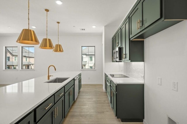 kitchen featuring stainless steel appliances, a sink, light countertops, decorative backsplash, and light wood finished floors