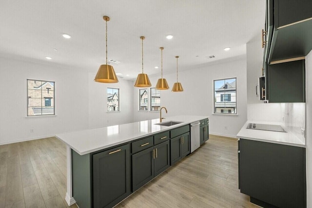 kitchen featuring light countertops, appliances with stainless steel finishes, a sink, and a center island with sink