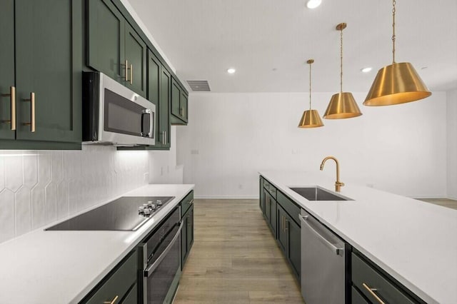 kitchen featuring a sink, visible vents, green cabinets, appliances with stainless steel finishes, and tasteful backsplash