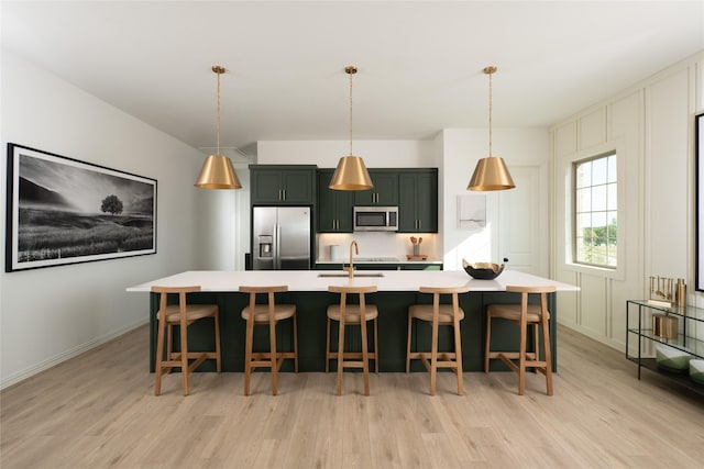 kitchen featuring a large island, sink, hanging light fixtures, stainless steel appliances, and a kitchen breakfast bar