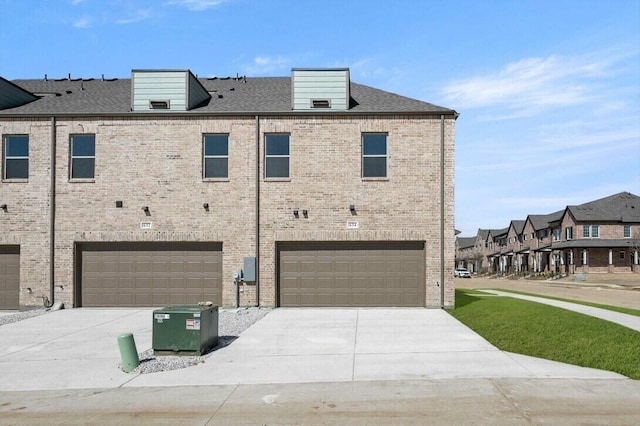 back of house with driveway, brick siding, and an attached garage