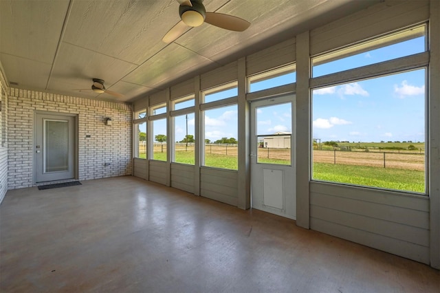 unfurnished sunroom with a rural view, wood ceiling, and ceiling fan