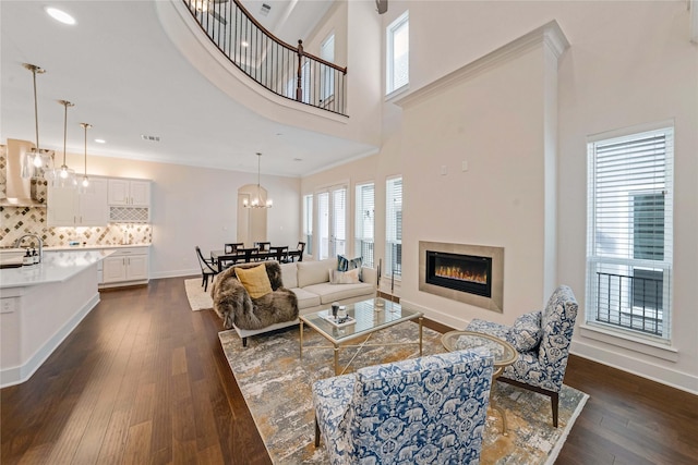 living room with dark hardwood / wood-style flooring, ornamental molding, sink, and a high ceiling