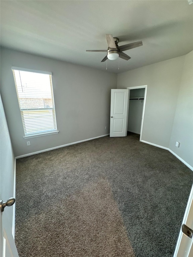 unfurnished bedroom featuring dark colored carpet, ceiling fan, and a closet