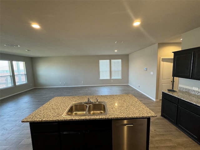 kitchen featuring light stone countertops, dishwasher, sink, an island with sink, and hardwood / wood-style flooring