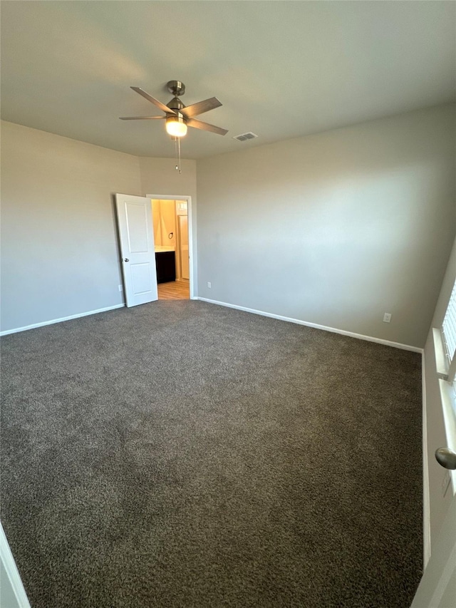 unfurnished room with dark carpet and ceiling fan