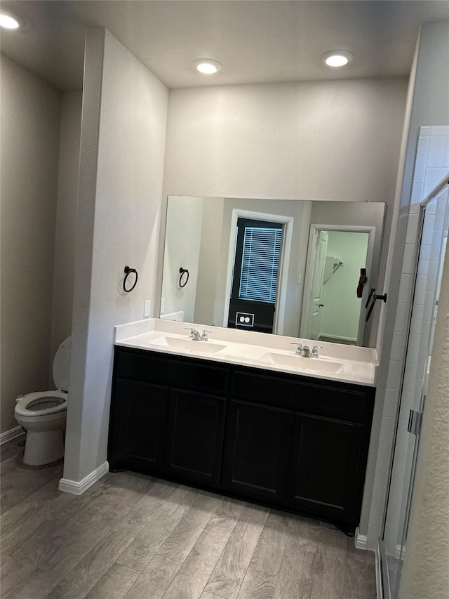 bathroom with a shower with door, wood-type flooring, vanity, and toilet