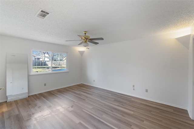 empty room featuring hardwood / wood-style flooring, ceiling fan, and a textured ceiling