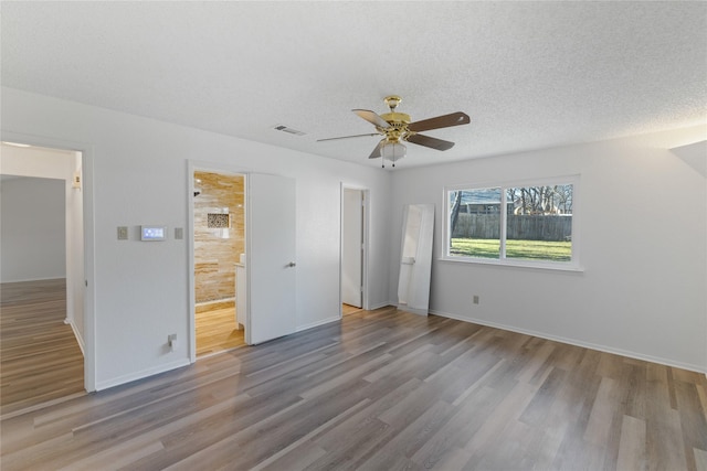 unfurnished bedroom with ceiling fan, ensuite bathroom, a textured ceiling, and light wood-type flooring