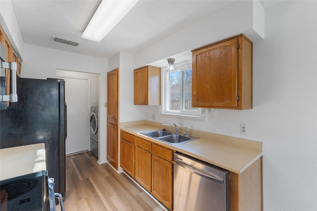 kitchen featuring black fridge, light hardwood / wood-style floors, sink, dishwasher, and washer / clothes dryer