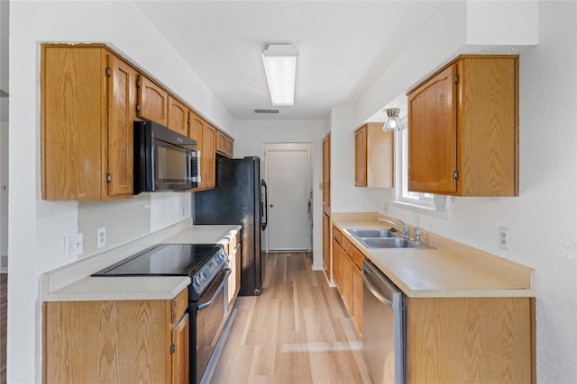 kitchen featuring black appliances, light hardwood / wood-style floors, and sink