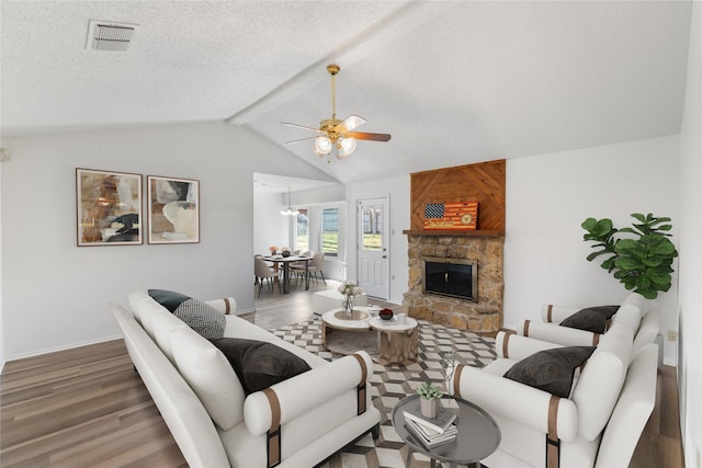 living room featuring ceiling fan, vaulted ceiling with beams, a textured ceiling, a fireplace, and hardwood / wood-style flooring