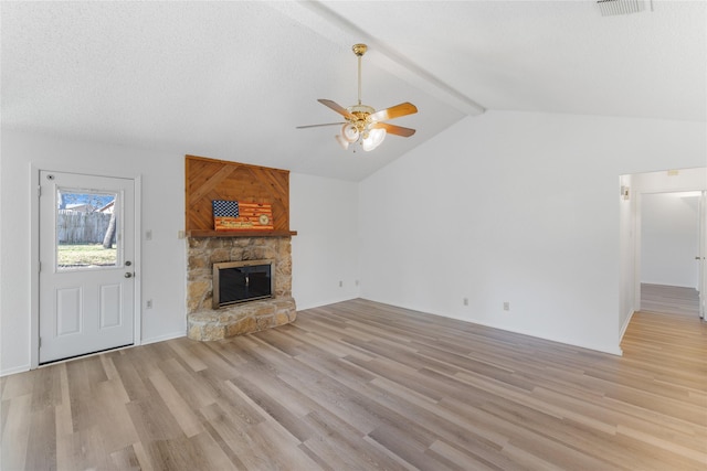 unfurnished living room with a textured ceiling, ceiling fan, light hardwood / wood-style flooring, a fireplace, and vaulted ceiling with beams