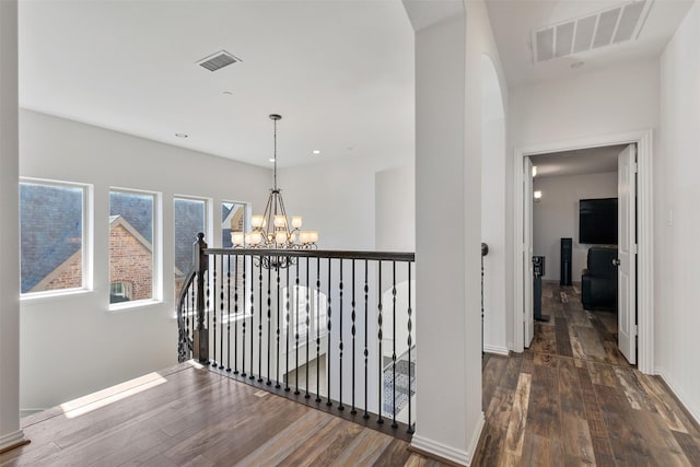 corridor with dark hardwood / wood-style floors and a chandelier