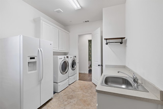 clothes washing area with sink, independent washer and dryer, and cabinets