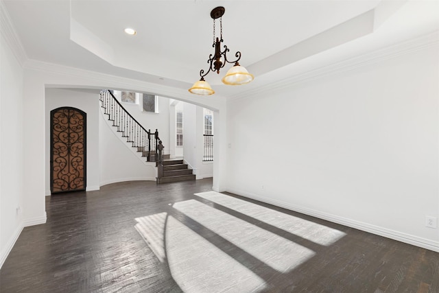 interior space with dark wood-type flooring, a raised ceiling, and an inviting chandelier