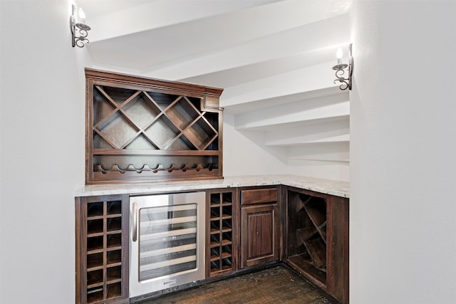 wine area with dark wood-type flooring, beverage cooler, and bar area