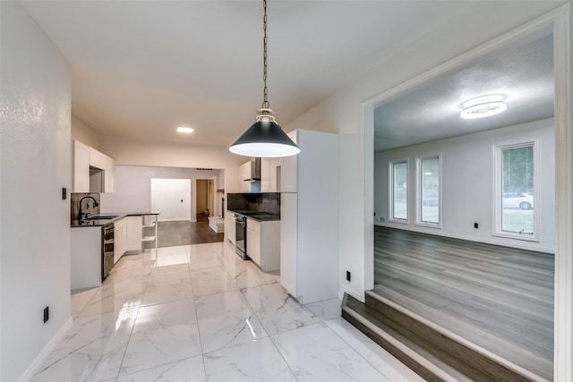 kitchen with pendant lighting, backsplash, electric stove, sink, and white cabinetry