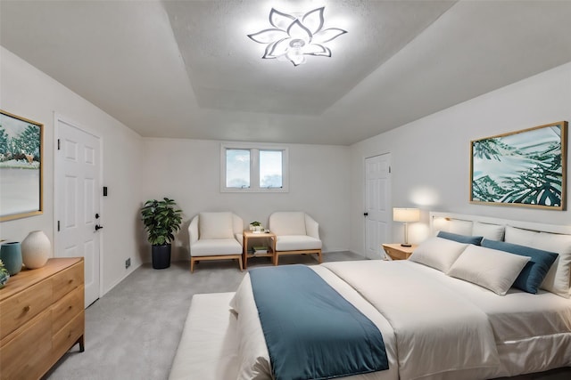 bedroom with a raised ceiling and light carpet