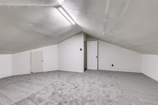 bonus room with light colored carpet, a textured ceiling, and vaulted ceiling