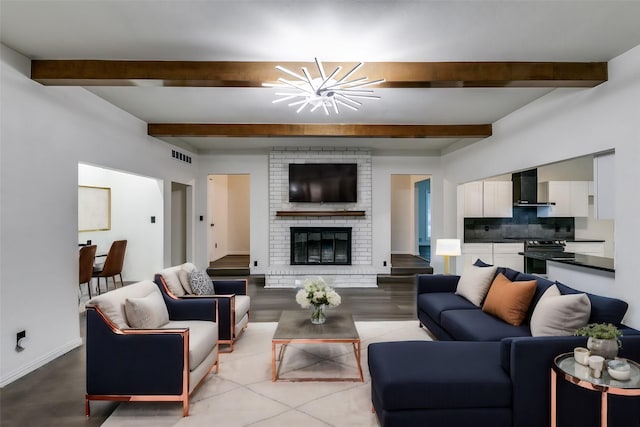 living room featuring a brick fireplace, beam ceiling, and an inviting chandelier