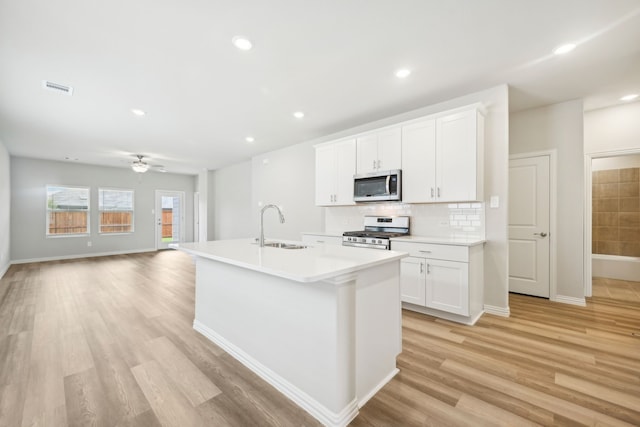 kitchen featuring white cabinets, a kitchen island with sink, sink, and appliances with stainless steel finishes