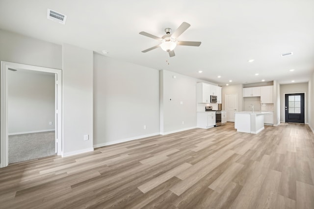 unfurnished living room featuring light hardwood / wood-style flooring, ceiling fan, and sink