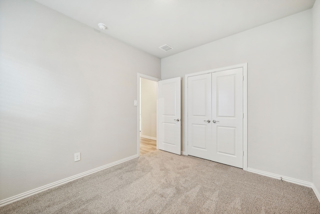 unfurnished bedroom featuring light carpet and a closet