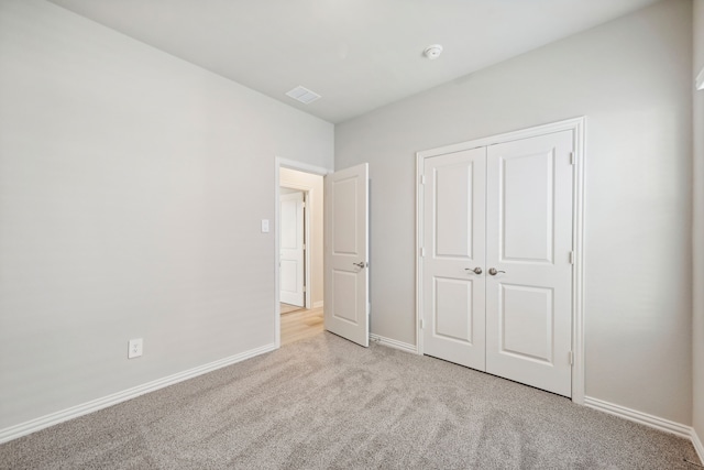 unfurnished bedroom featuring a closet and light colored carpet