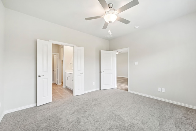 unfurnished bedroom featuring ceiling fan, light carpet, and connected bathroom