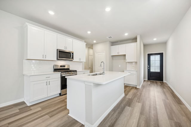 kitchen with a center island with sink, white cabinets, sink, and appliances with stainless steel finishes