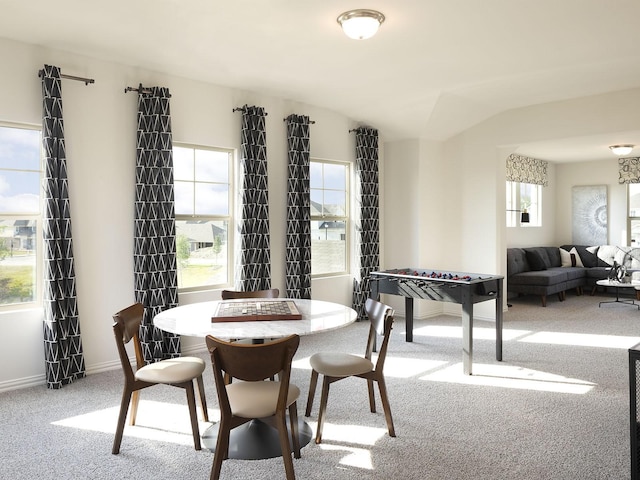 carpeted dining room with vaulted ceiling