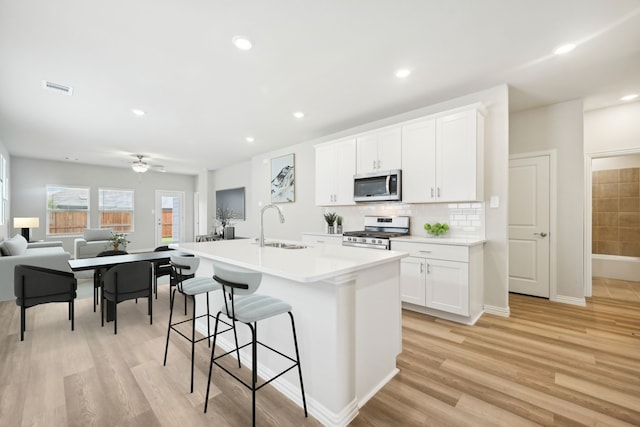 kitchen with white cabinetry, sink, a kitchen breakfast bar, a kitchen island with sink, and appliances with stainless steel finishes