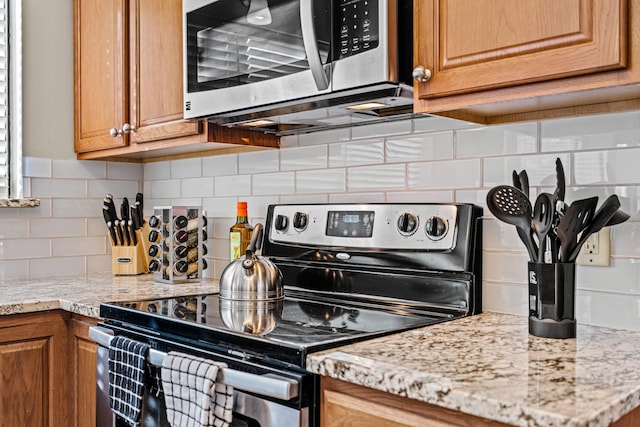 kitchen featuring light stone counters, stainless steel appliances, and tasteful backsplash