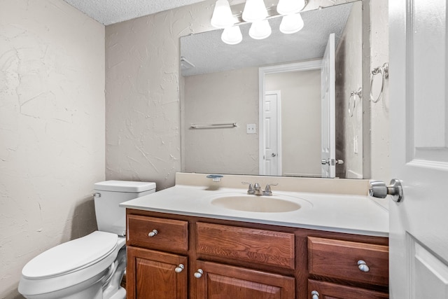 bathroom with vanity, a textured ceiling, and toilet