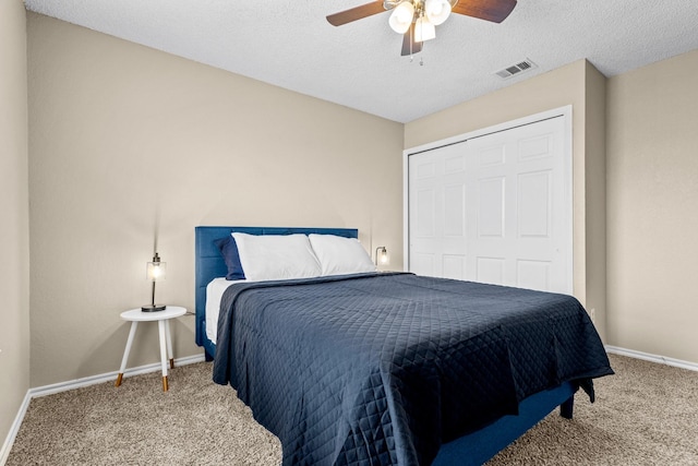 bedroom featuring carpet flooring, ceiling fan, a closet, and a textured ceiling