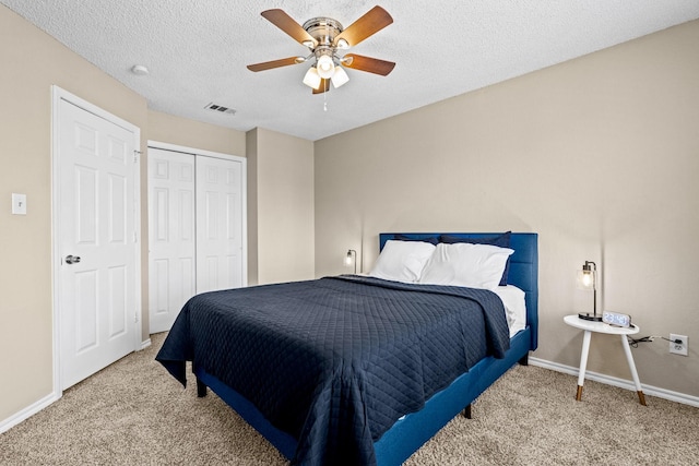 bedroom with carpet flooring, ceiling fan, a closet, and a textured ceiling